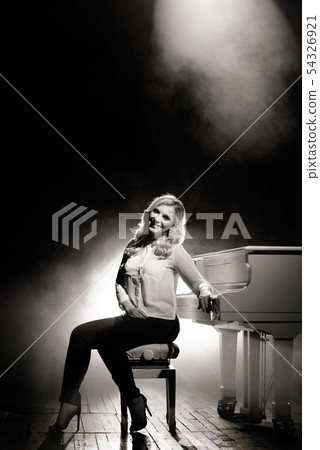 Pianist posing near white piano on the stage Pianist posing near white piano on the stage 54326921