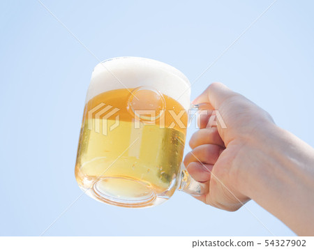 拿著在藍天的一個人的手一個啤酒杯 54327902
