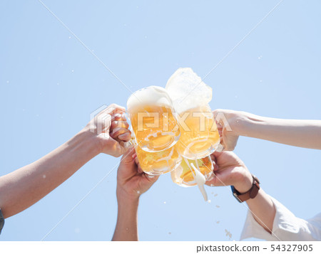 Hand of four men and women toasting with beer under blue sky 54327905