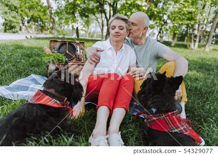 Happy man and woman sitting on the plaid in the park 54329077