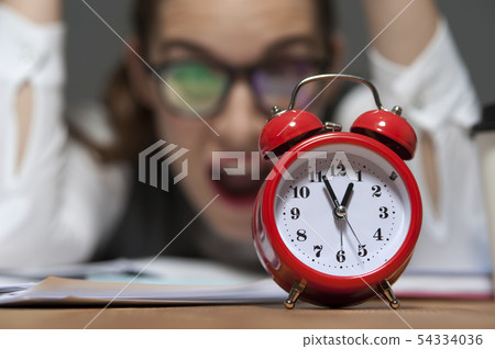 Portrait of hurried young businesswoman ooking at red retro styled clock 54334036