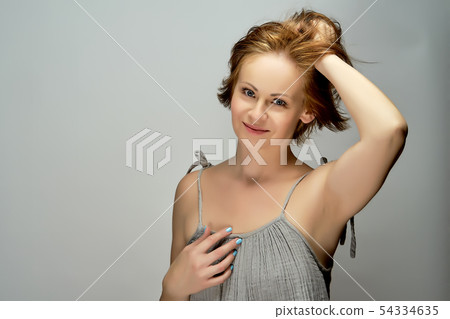Beautiful attractive red-haired woman poses in studio on gray background. Beautiful attractive red-haired woman poses in studio on gray background. 54334635