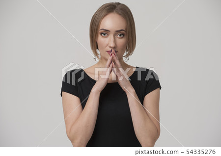 Portrait of thoughtful young woman pointing her fingers to lips Portrait of thoughtful young woman pointing her fingers to lips 54335276