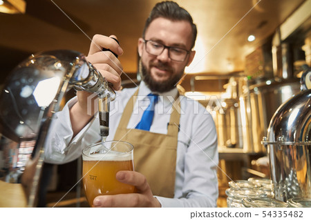 Barman pouring lager beer in cold glass. Barman pouring lager beer in cold glass. 54335482