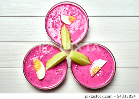 Three glass bowls with delicious cold beetroot soup on white table. Three glass bowls with delicious cold beetroot soup on white table. 54335854