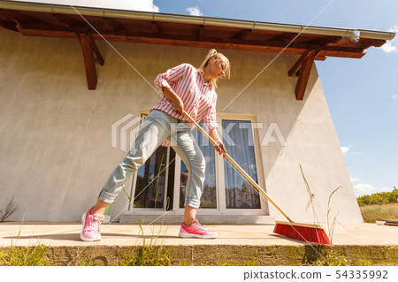 Woman cleaning patio using brush broom 54335992