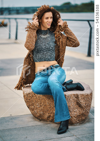 Beautiful young woman posing on stone bench on the promenade at the river Beautiful young woman posing on stone bench on the promenade at the river 54336388