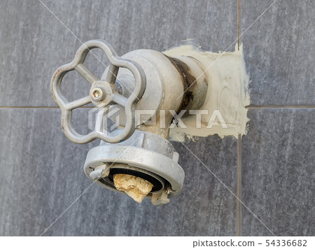 Fire hydrant on an outer wall with stone into it 54336682