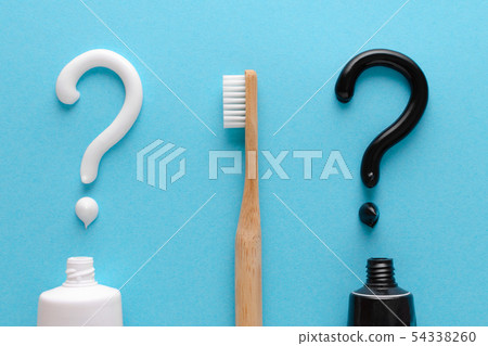 question from white and black toothpaste, teeth care concept, wooden toothbrush on blue background 54338260