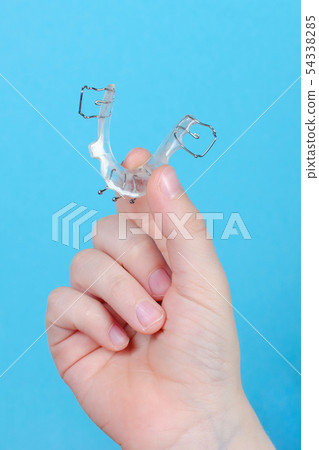 child's hand with orthodontic appliance on blue background child's hand with orthodontic appliance on blue background 54338285