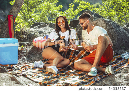 Young couple having picnic at riverside in sunny day 54338587