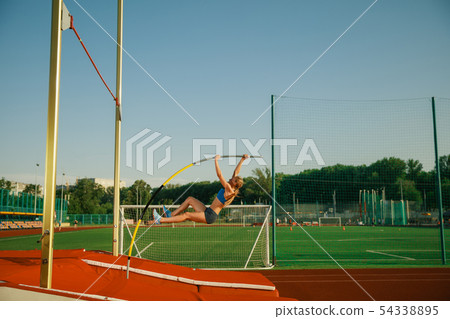 Female high jumper training at the stadium in sunny day Female high jumper training at the stadium in sunny day 54338895