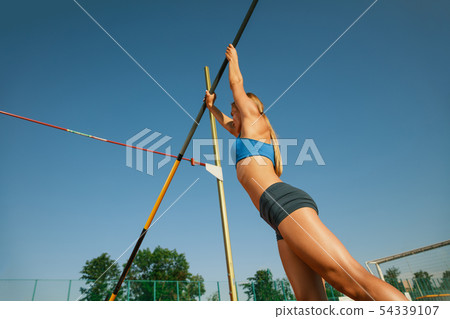 Female high jumper training at the stadium in sunny day Female high jumper training at the stadium in sunny day 54339107