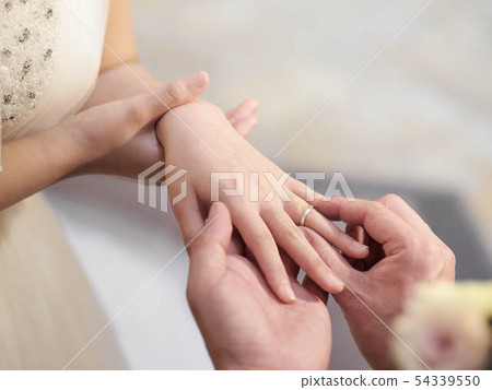 Hands of the bride and groom exchanging rings 54339550