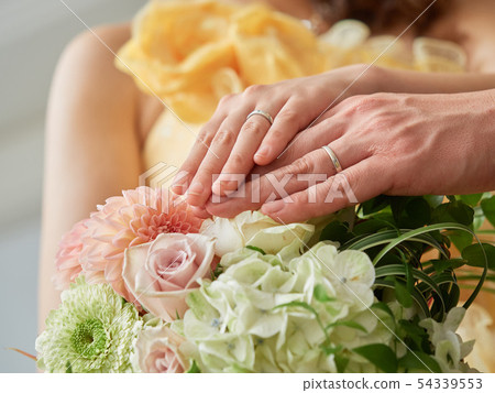 Bride and groom putting their hands on the bouquet 54339553