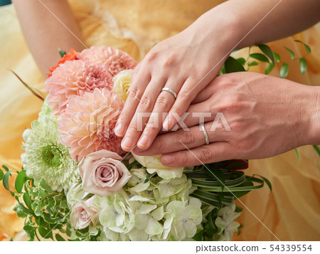Bride and groom putting their hands on the bouquet 54339554