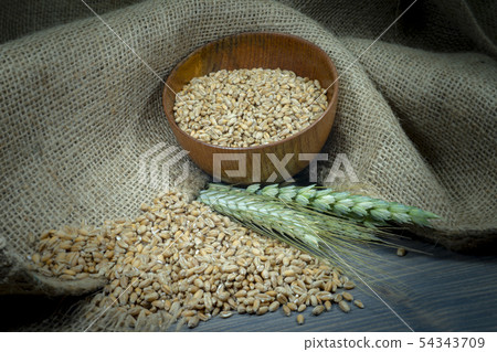 Wheat seeds spilling from a bowl with ears Wheat seeds spilling from a bowl with ears 54343709