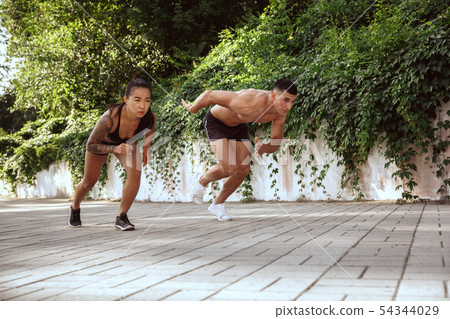 A muscular athletes doing workout on the city's street or park A muscular athletes doing workout on the city's street or park 54344029