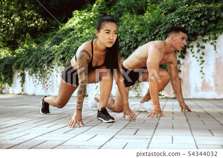 A muscular athletes doing workout on the city's street or park A muscular athletes doing workout on the city's street or park 54344032