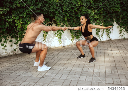 A muscular athletes doing workout on the city's street or park A muscular athletes doing workout on the city's street or park 54344033
