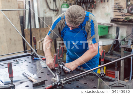 Worker in Metal workshop with tools and workpiece 54345980