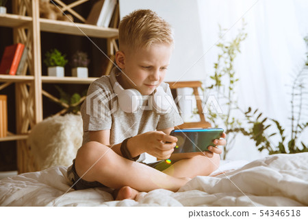 Little boy using different gadgets at home Little boy using different gadgets at home 54346518