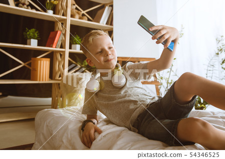 Little boy using different gadgets at home Little boy using different gadgets at home 54346525