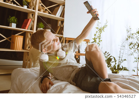 Little boy using different gadgets at home Little boy using different gadgets at home 54346527