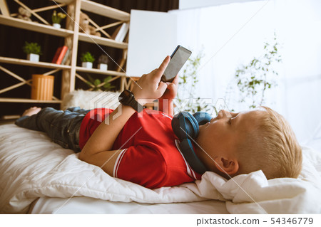 Little boy using different gadgets at home Little boy using different gadgets at home 54346779