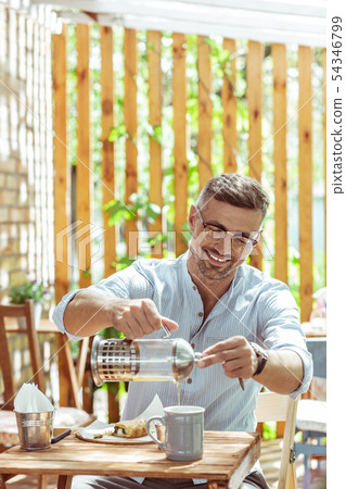 Smiling man drinking tea in a summer cafe. 54346799