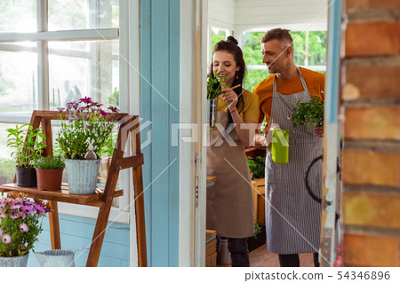 Two coworkers standing behind the doorway of flower shop. 54346896