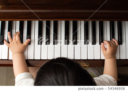 Baby's hands playing a piano, finger 54346936
