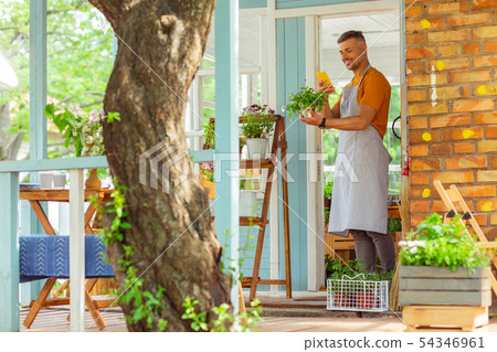 Florist taking pictures of a plant with his smartphone. 54346961
