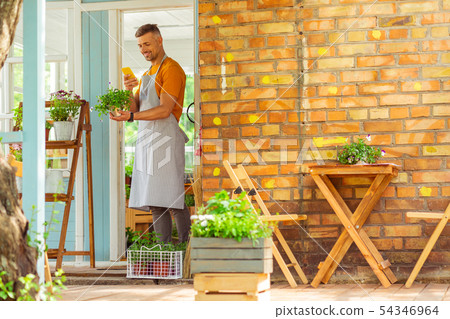 Plantsman standing on a terrace and taking pictures. 54346964