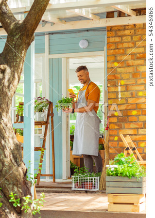 Florist standing on the shop porch photographing his plant. 54346966
