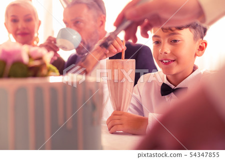 Close up of dark-eyed birthday boy sitting near grandparents 54347855