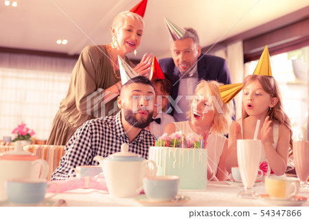 Handsome dark-haired man blowing candles celebrating birthday 54347866