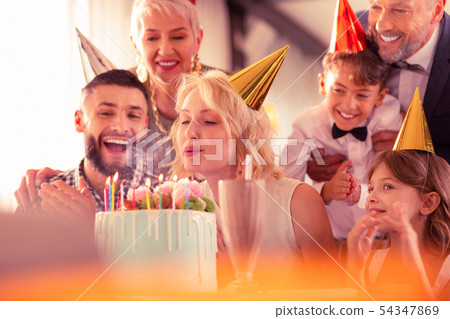 Family feeling excited while birthday woman blowing candles 54347869