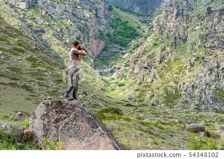 Male hiker takes photo of beautiful mountains in North Caucasus in summer Male hiker takes photo of beautiful mountains in North Caucasus in summer 54348102