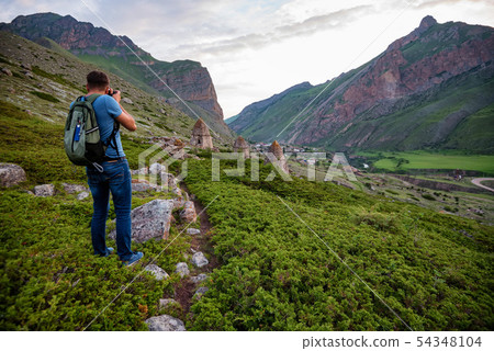 Male hiker takes photo of beautiful mountains and ancient tombs. North Caucasus 54348104