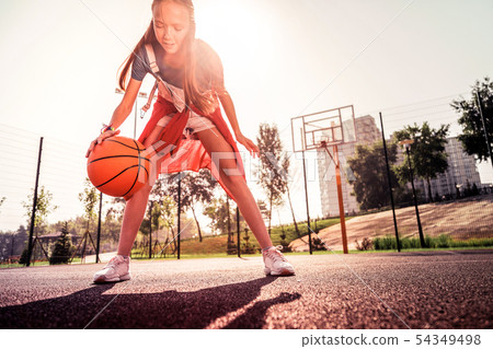Skilled young basketball player showing her technique Skilled young basketball player showing her technique 54349498