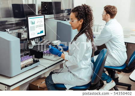 Serious dark haired woman holding a special scanner Serious dark haired woman holding a special scanner 54350402