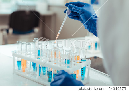 Close up of a scientist hand above test tubes Close up of a scientist hand above test tubes 54350575