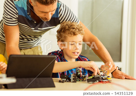 Pleasant intelligent man standing behind the boy 54351129