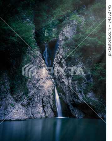 A tall waterfall falls from a cliff at night 54352745