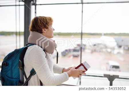 Woman with a backpack and a travel pillow looks on 54353052