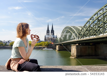 Young woman eats traditional pretzel sitting on Young woman eats traditional pretzel sitting on 54353143