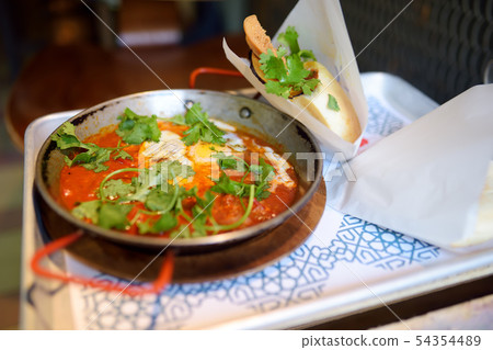 Shakshuka at pan on tray in cafe of Israeli 54354489