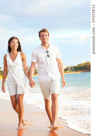 Casual couple walking on beach holding hands Casual couple walking on beach holding hands 54355613