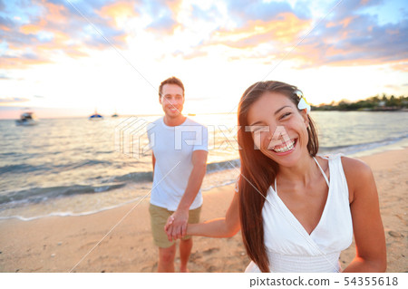 Happy couple on beach holding hands at sunset Happy couple on beach holding hands at sunset 54355618
